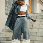 Confident young woman in chic outfit posing outdoors in a lively urban environment.
