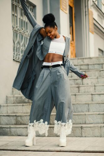 Confident young woman in chic outfit posing outdoors in a lively urban environment.